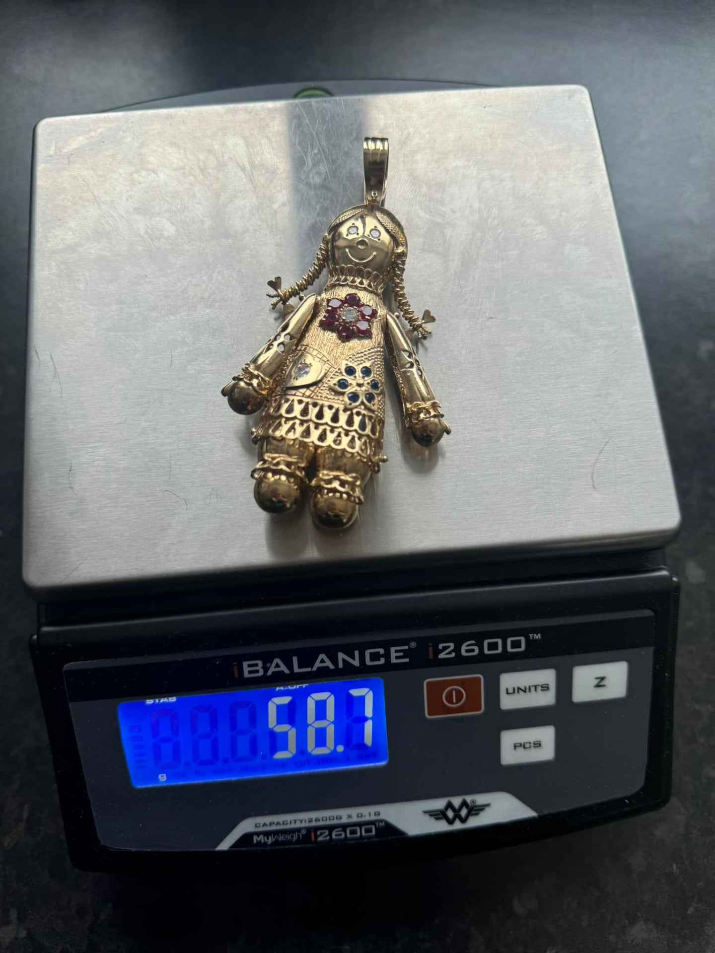 Ornate gold doll pendant with ruby and sapphire detailing on the scales