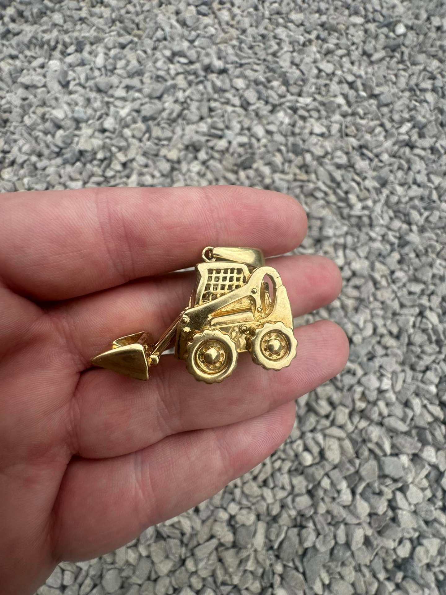 Solid gold digger pendant held in a hand