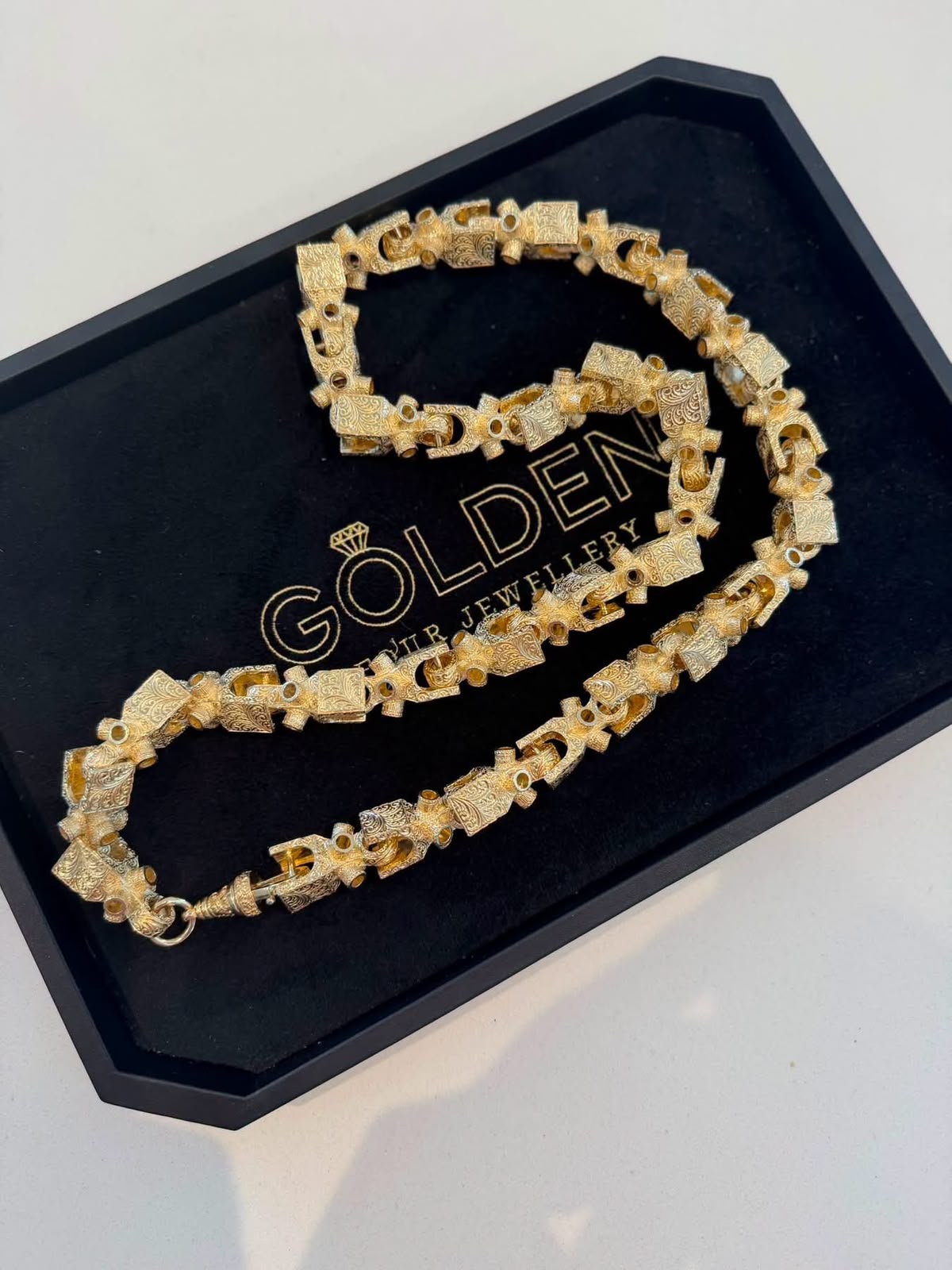Intricately detailed gold chain presented on a Golden Four Jewellery tray